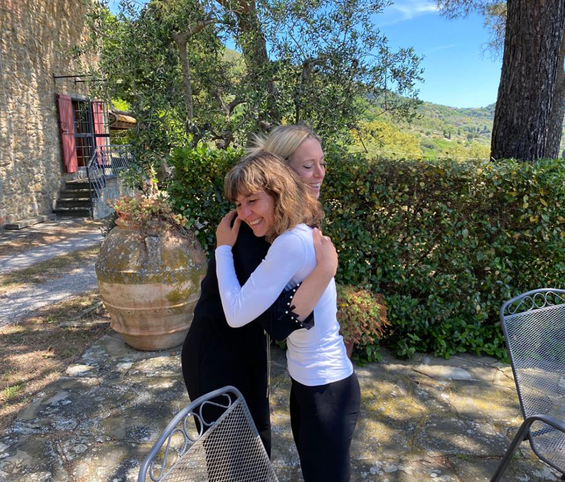 Due persone si abbracciano su un patio in pietra con giardino e vista sulla campagna.
